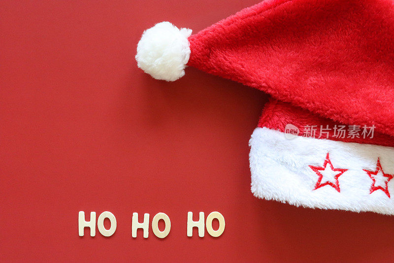 自制DIY简易圣诞卡设计的图像，红色背景上剪出白色字母，手工制作的节日圣诞贺卡，圣诞老人的帽子Ho Ho Ho消息，复制空间